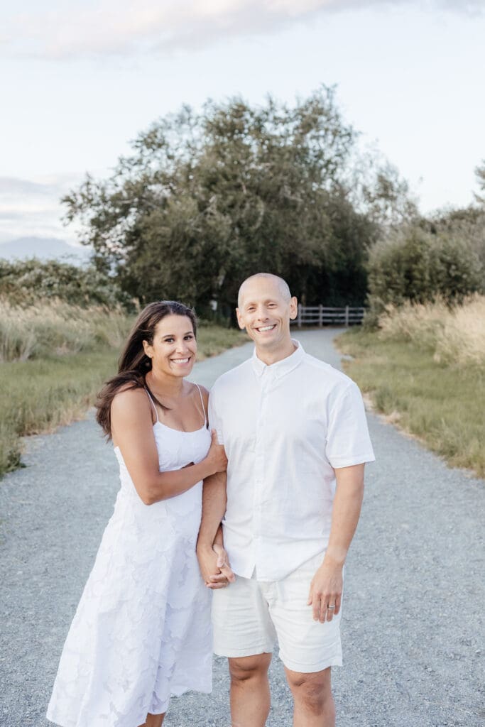 Parents posing together on a quiet trail, holding hands and smiling — modern couple portrait by Maple Ridge photographer Meliza Orellana