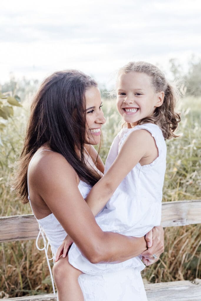 Mother hugging and tickling daughter while laughing — candid family portrait at sunset in Willband Creek Park in Abbotsford