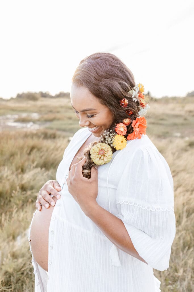 Maternity session by the water at sunset with soft neutral tones and natural light