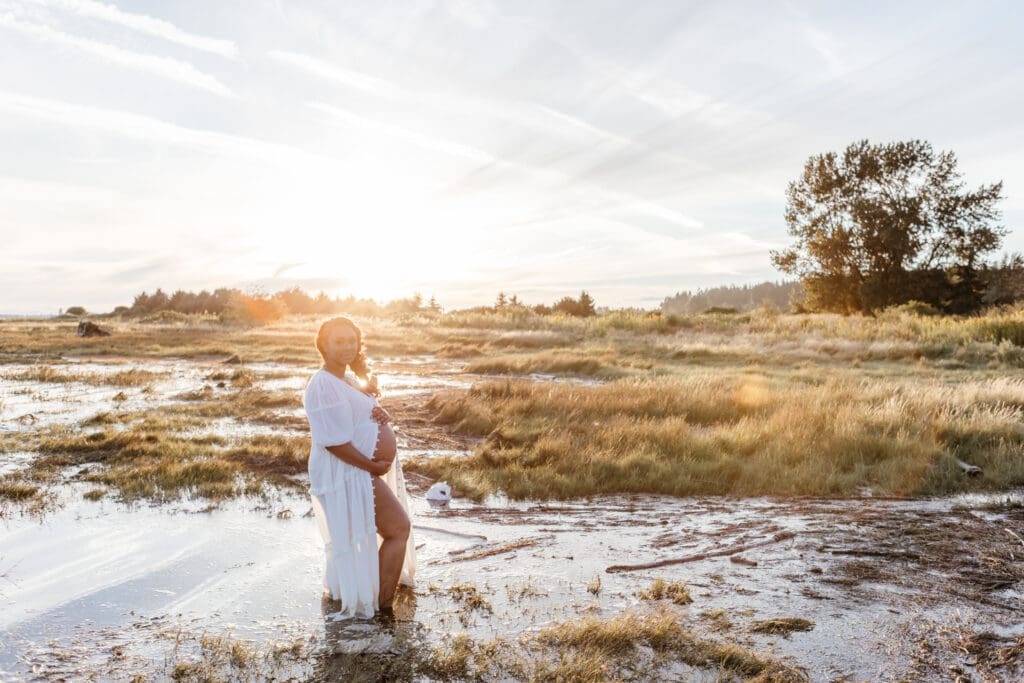 Expectant mother wearing a neutral white maternity dress for an outdoor photo session