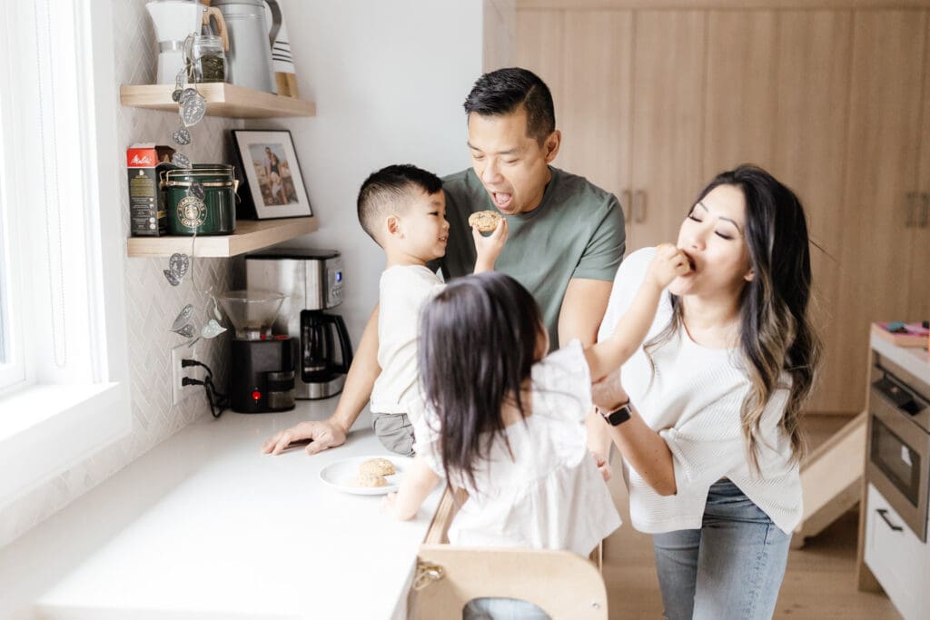 Parents helping their children bake at the kitchen counter.