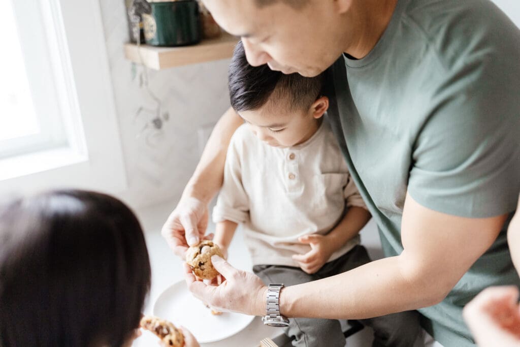 Parents helping their children bake at the kitchen counter.