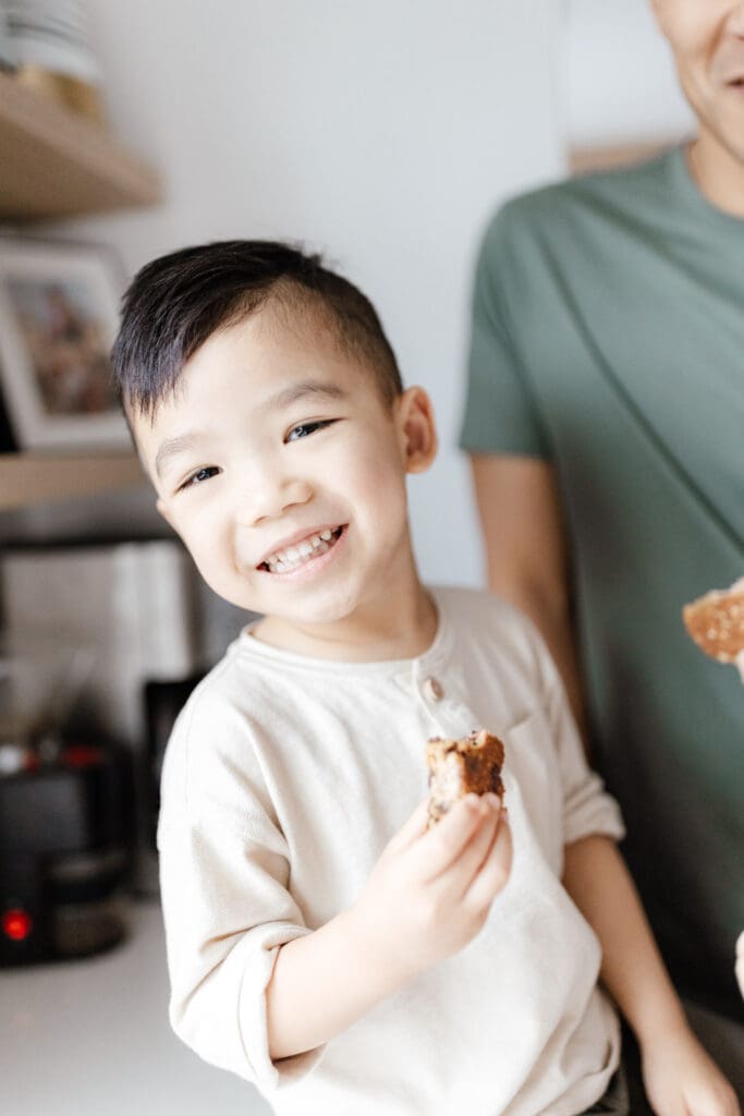 Smiling young boy holding a treat in the kitchen.