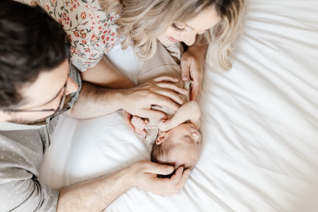 Close-up of parents holding newborn wrapped in a simple neutral outfit
