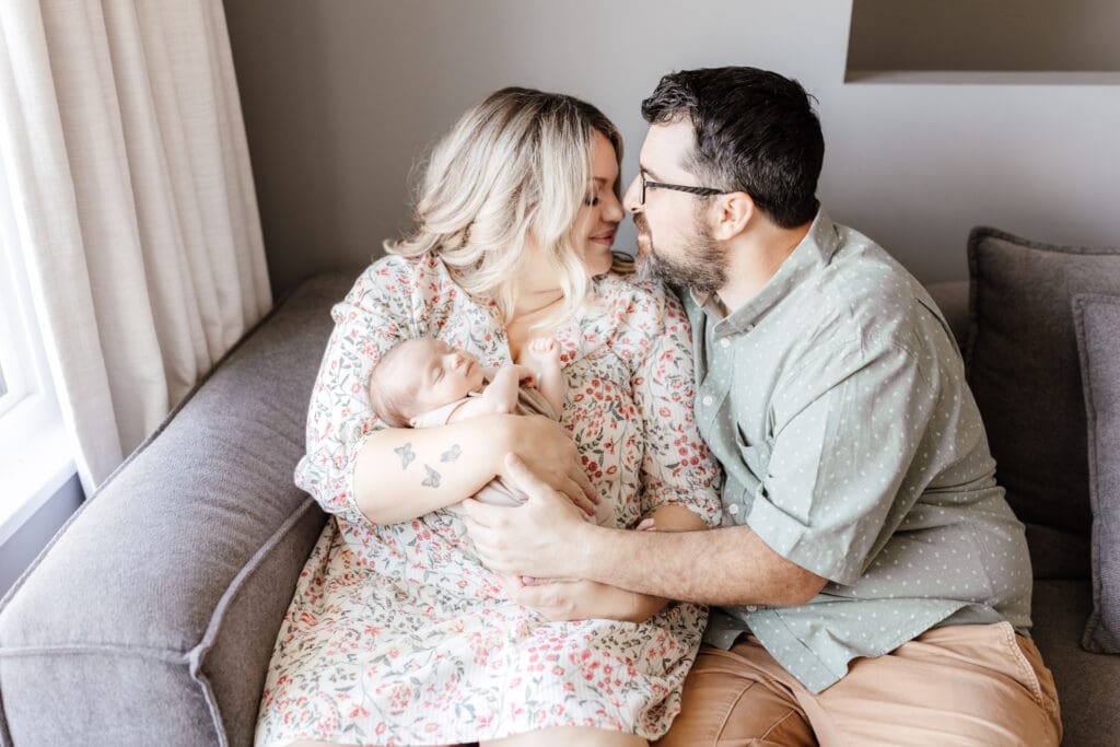 Close-up of parents holding newborn wrapped in a simple neutral outfit