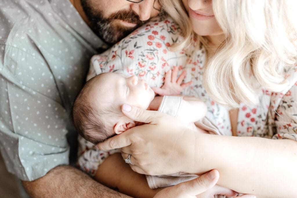 Close-up of newborn being held with parents partially visible