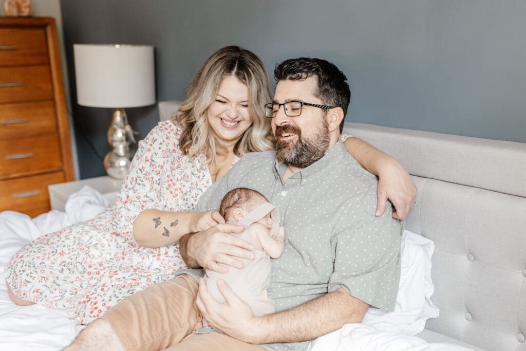 Family cuddling on a bed with their dog during an in-home newborn session