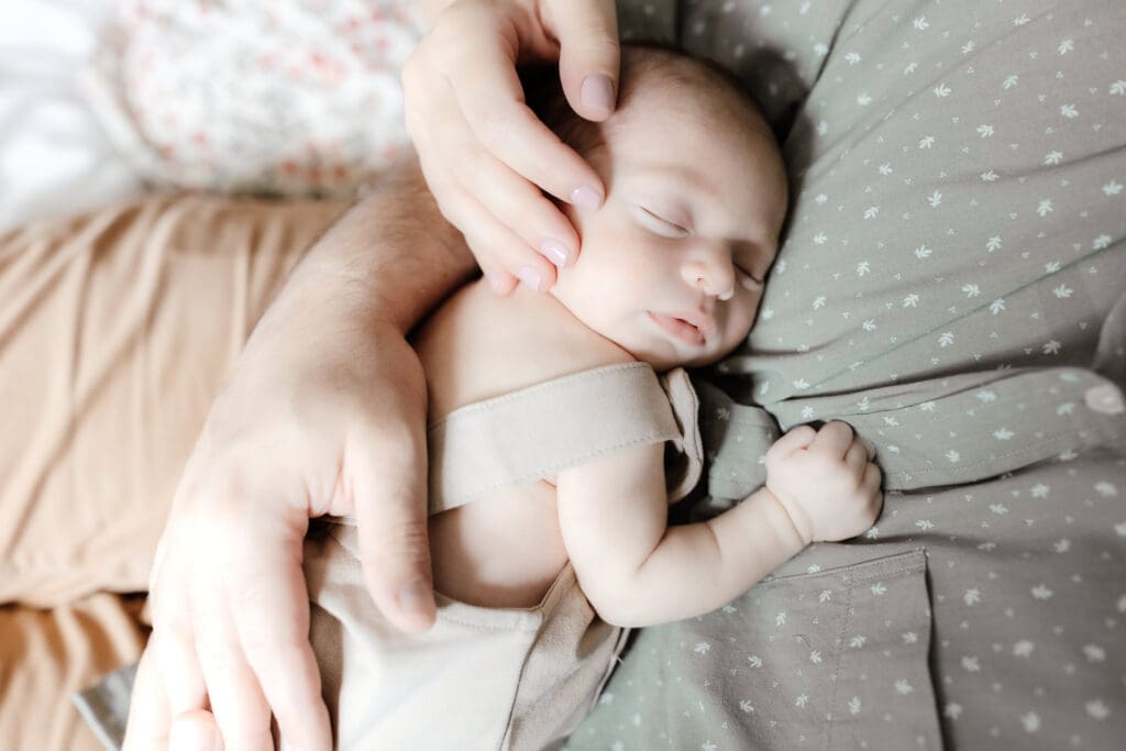 Close-up of newborn sleeping peacefully in his father's arms