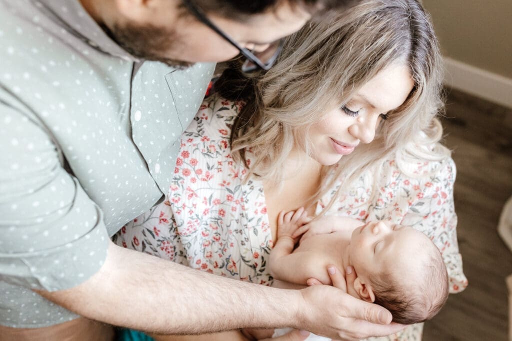 Parent gently holding newborn’s head during an in-home session