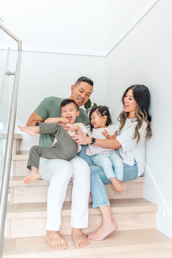 Family of four cuddling and playing together on their staircase.