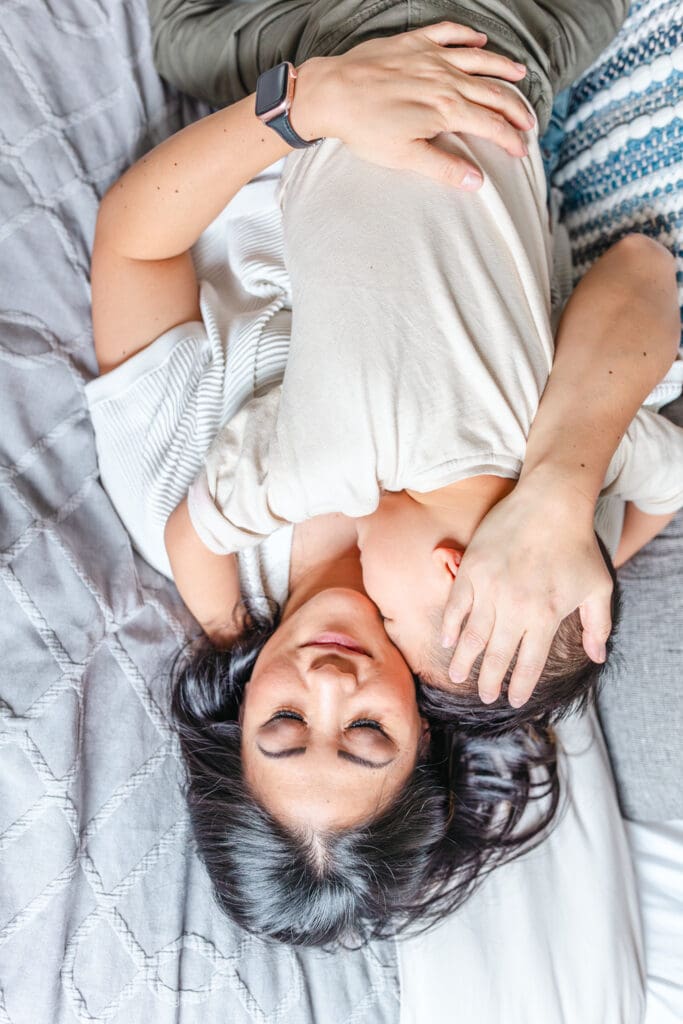 Mother and son snuggling on the bed in a quiet moment during an in-home photo shoot.