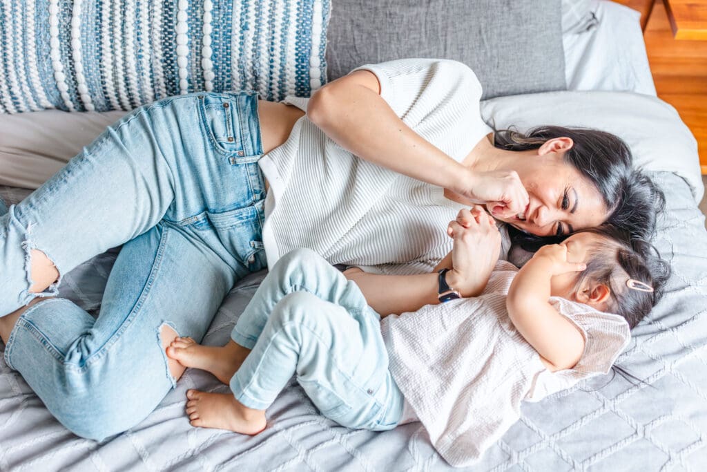 Mom and daughter snuggling on bed in light and airy in-home session showing outfit ideas for a light and natural aesthetic