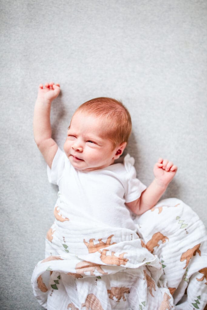 Newborn lying on a soft swaddle wearing a simple white outfit