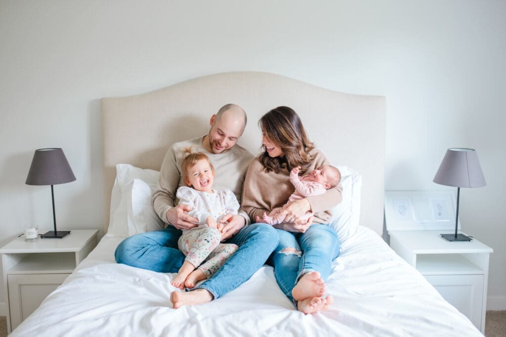 Family laughing and wearing coordinated neutral outfits during an in-home newborn family photography session near Vancouver