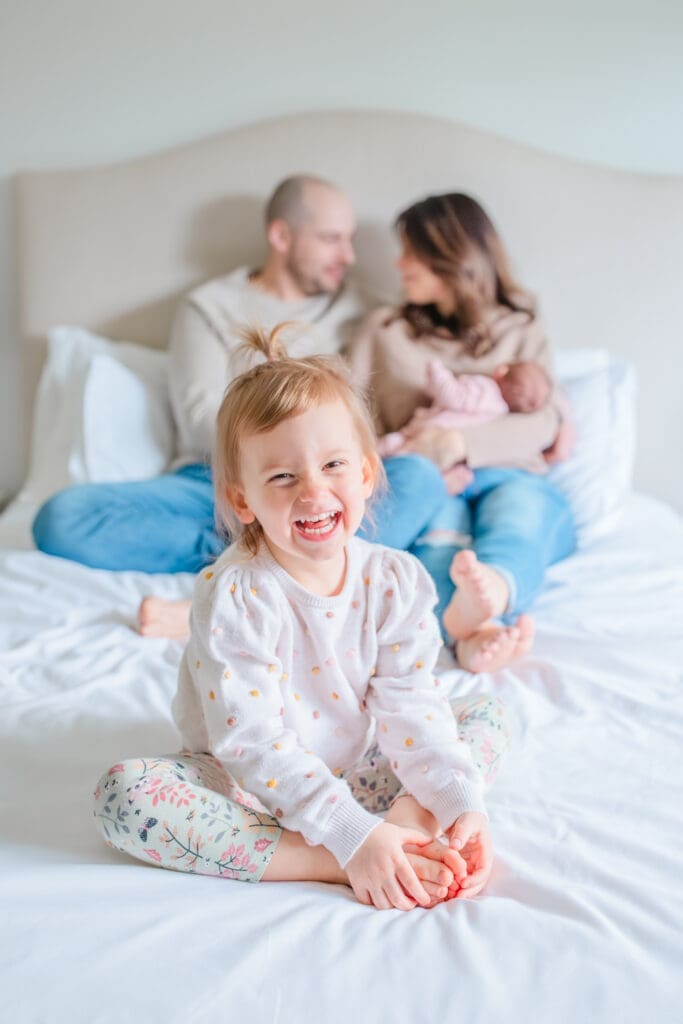 Children wearing soft, neutral clothing for in-home family photos with toddler and a newborn