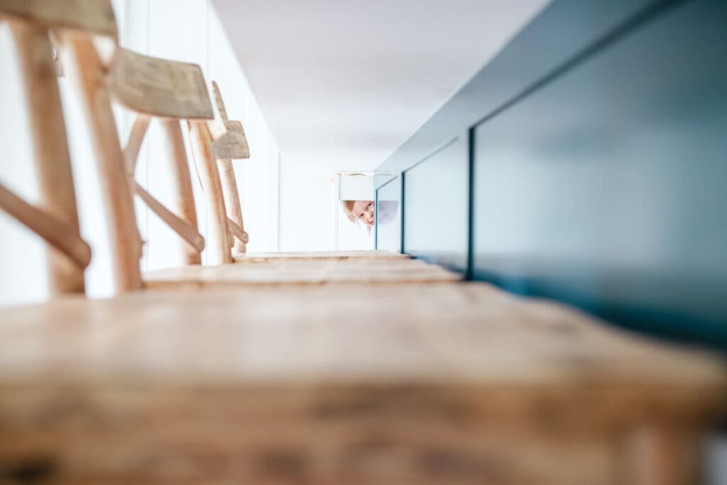 Toddler playfully hiding in a light and bright kitchen during a lifestyle family photo session in the Vancouver Area