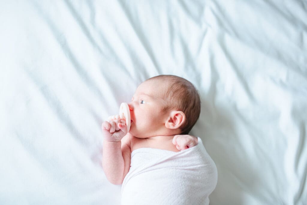 Newborn laying on bed in the soft morning light during lifestyle newborn session with Meliza Orellana