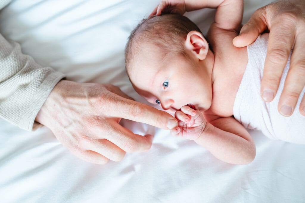 Parents wearing soft neutral tones during an in-home newborn photography session