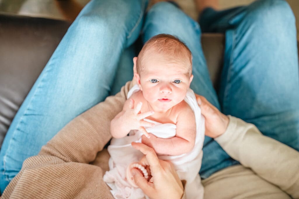 Lifestyle newborn photography with parents wearing simple, comfortable clothing at home