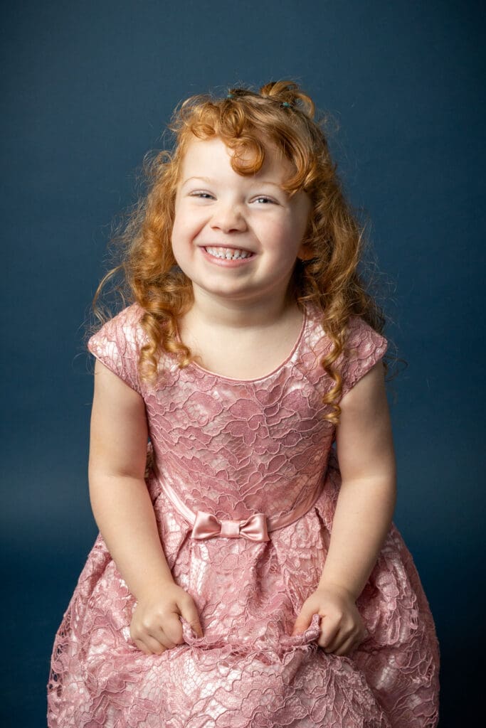 Daycare portrait of smiling toddler on dark blue background during daycare photo day
