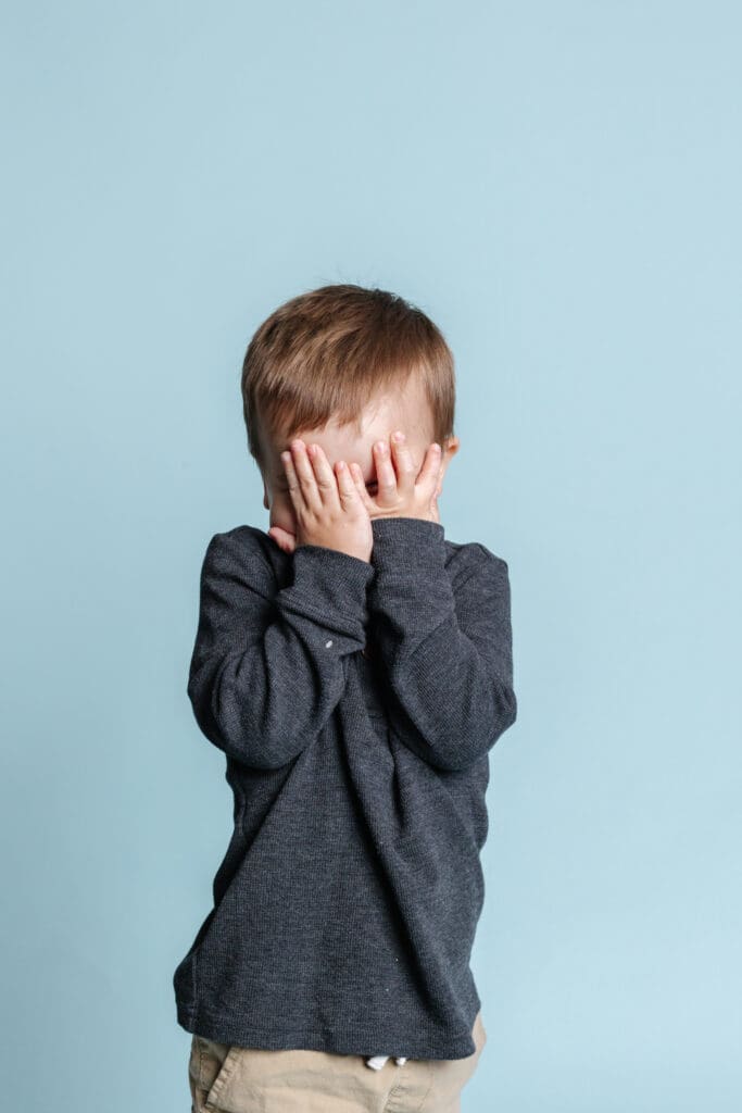 child hiding their face during daycare photo shoot because they're playing peek a boo