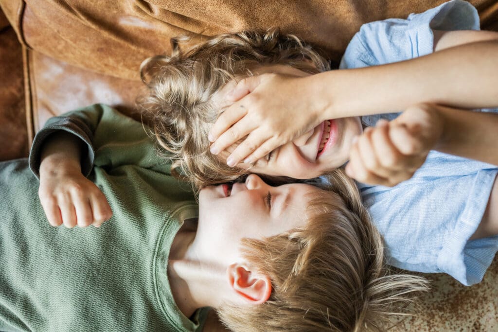brothers playing on the couch and laughing in a natural light and airy family photo session in-home