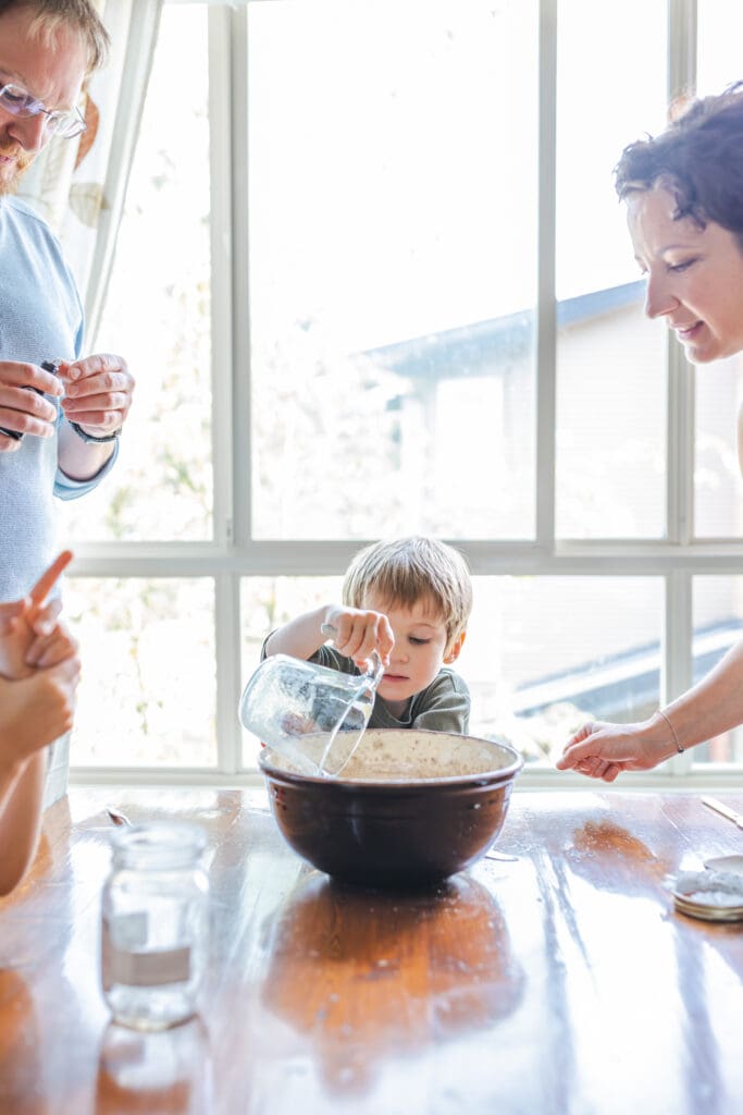 family baking together at kitchen table during documentary-style in-home family photography in west vancouver