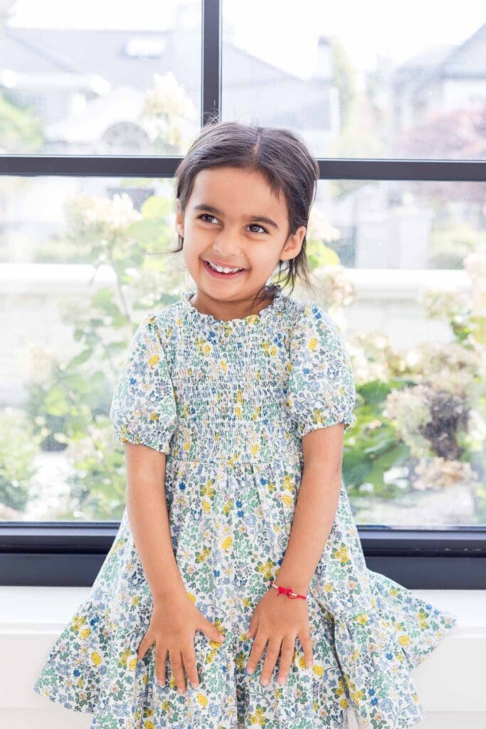 Young child sitting in a window sill during an in-home family photography photo shoot. 