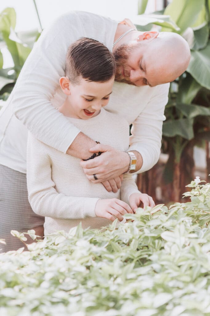 Dad holding his son during a natural family photography session in a Vancouver greenhouse