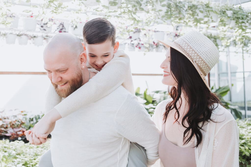 smiling family of three in a natural photo in a greenhouse