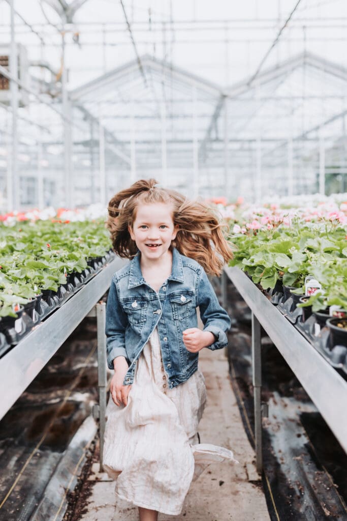 Joyful and unposed moment of child captured in soft natural light in greenhouse