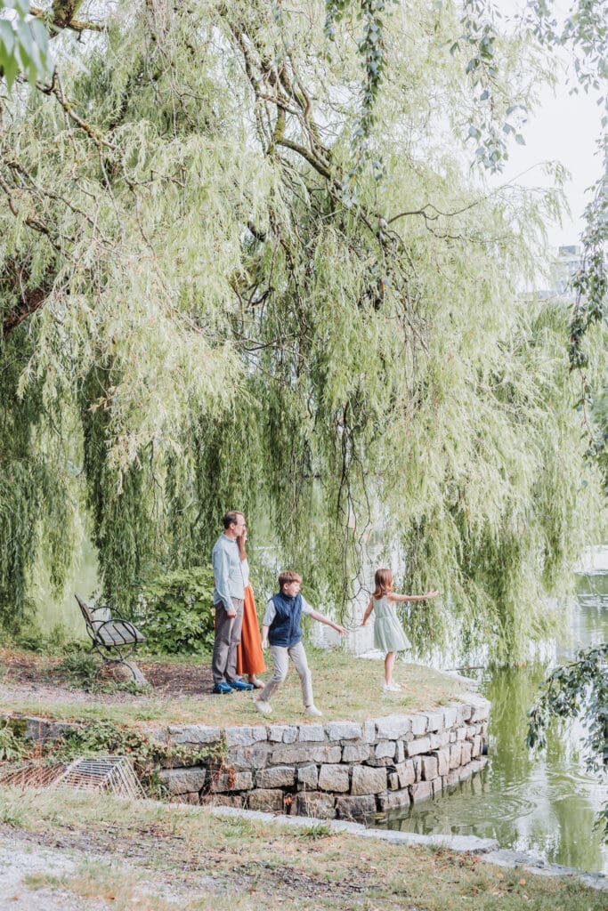 Family of four throwing rocks into Lost Lagoon during their Vancouver vacation