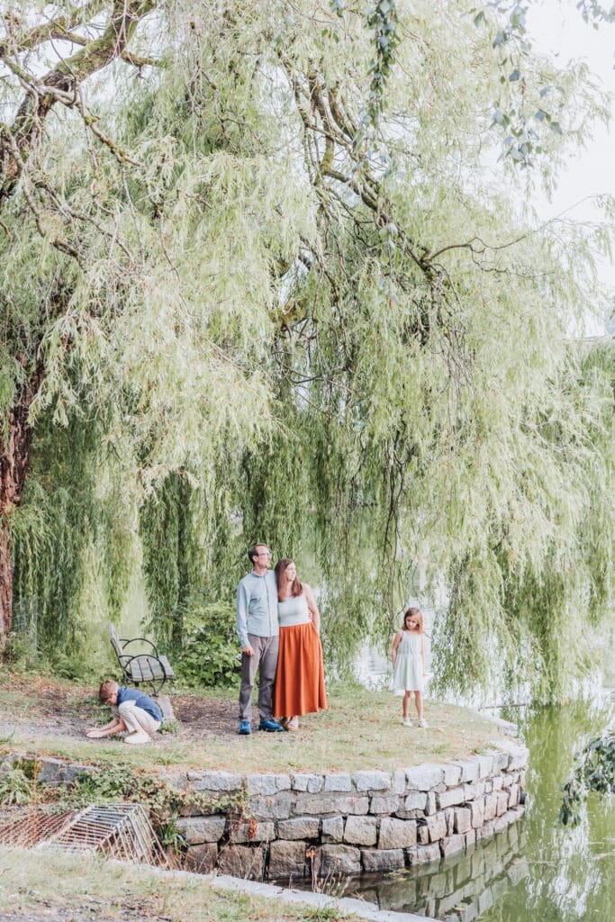 Family of four throwing rocks into Lost Lagoon during their Vancouver vacation