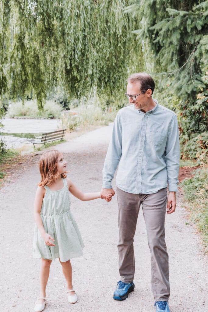 Father and daughter walking on trail at lost lagoon in vancouver