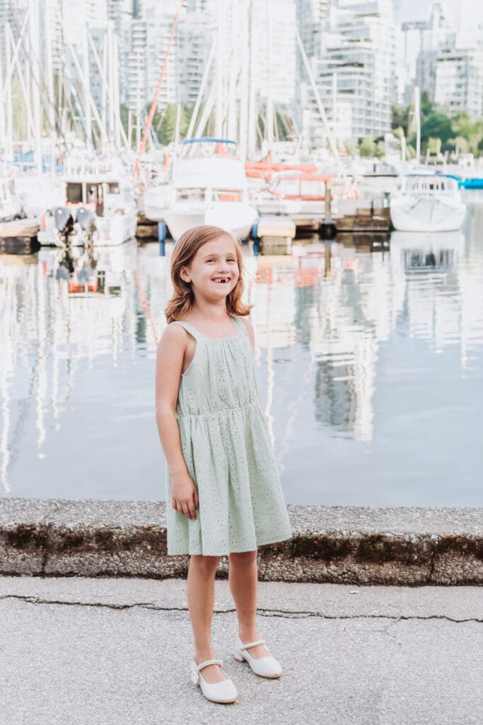 young girl smiling along the Stanley Park Seawall at the marina