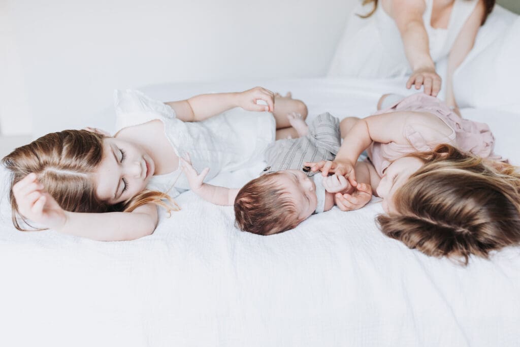 Toddlers cuddling newborn sibling during Surrey family photography session