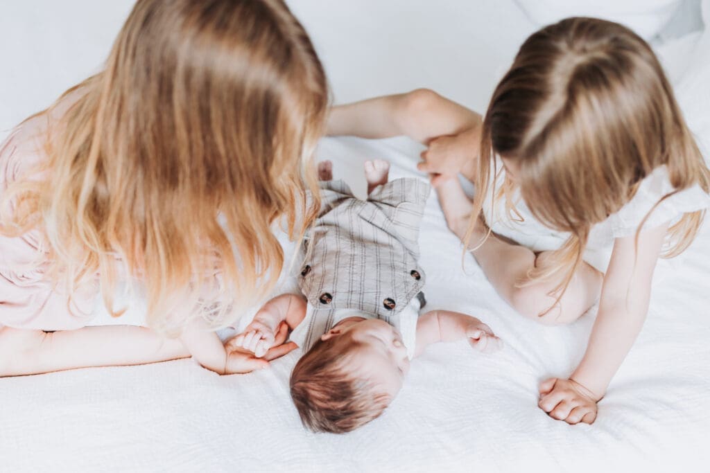 Toddlers cuddling newborn sibling during Surrey family photography session