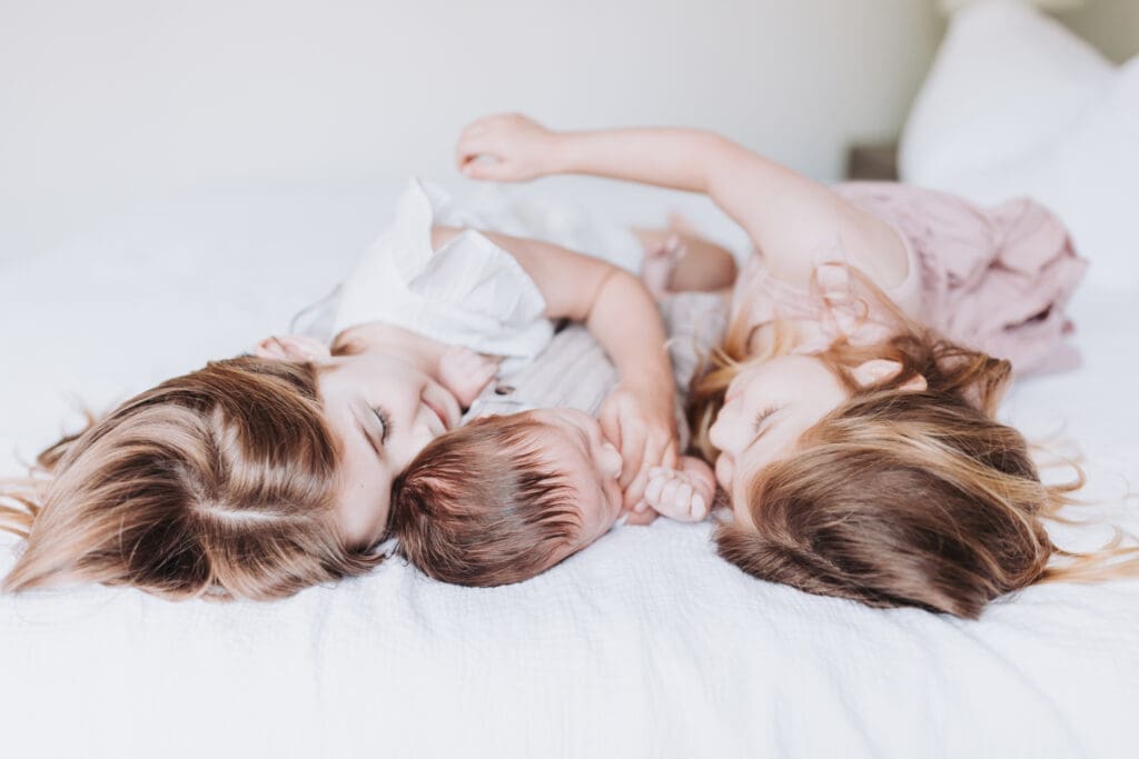 Toddlers cuddling newborn sibling during Surrey family photography session