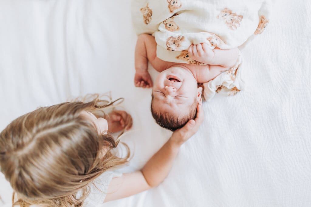 Toddlers cuddling newborn sibling during Surrey family photography session