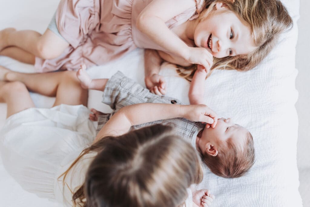 Toddlers cuddling newborn sibling during Surrey family photography session