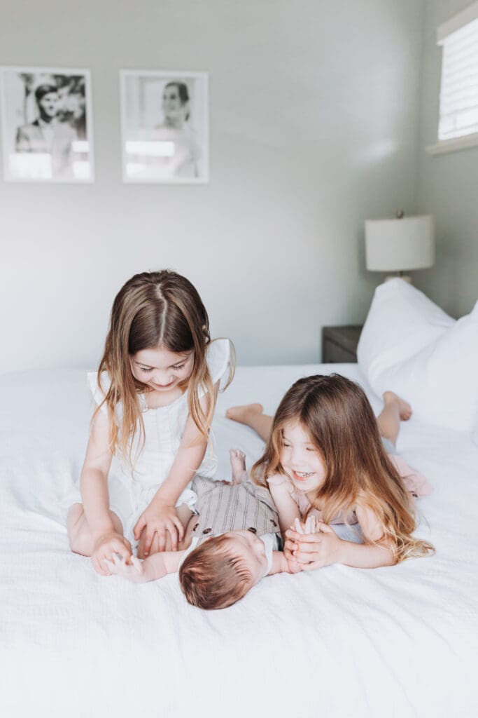 Toddlers cuddling newborn sibling during Surrey family photography session
