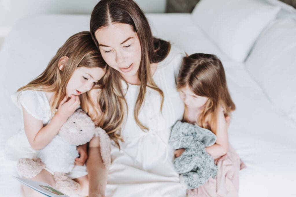 Mom reading with two toddlers during an in-home newborn session